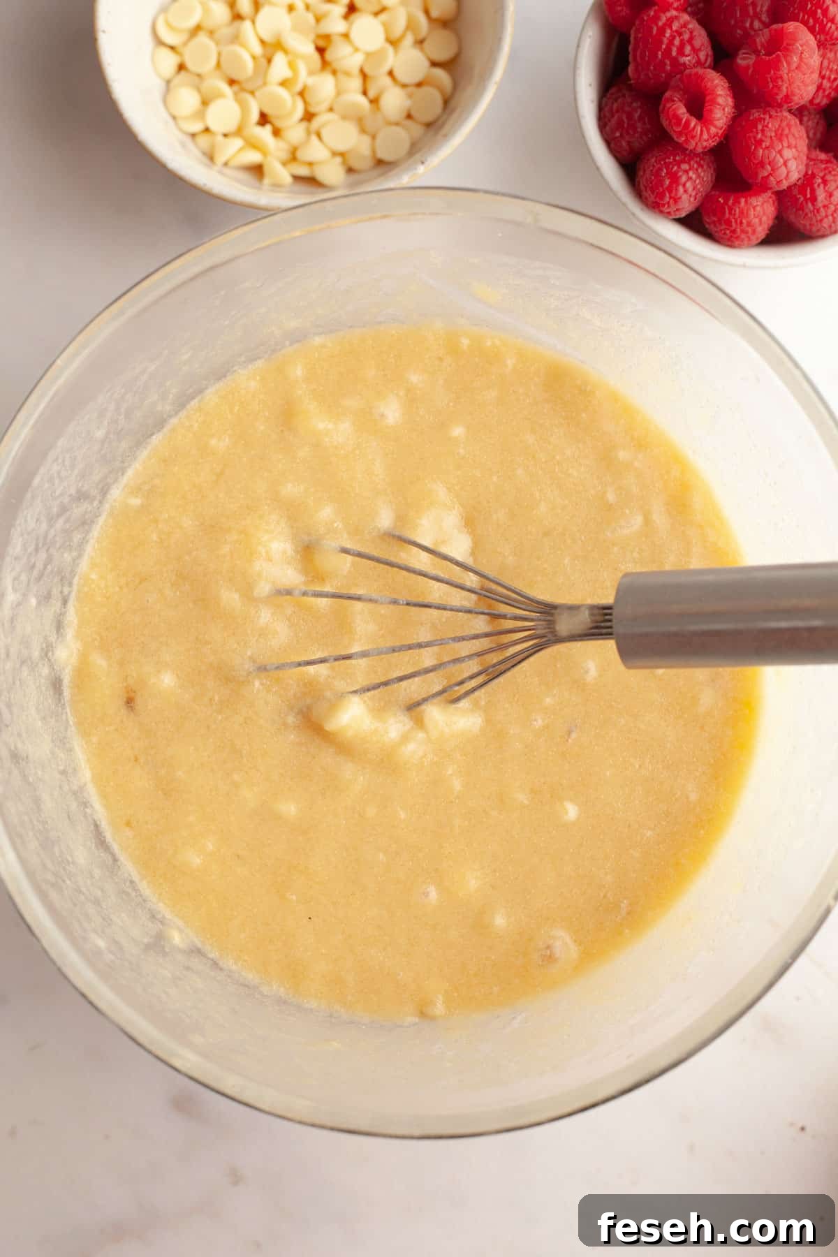 A bowl with banana muffin batter in it and a whisk.
