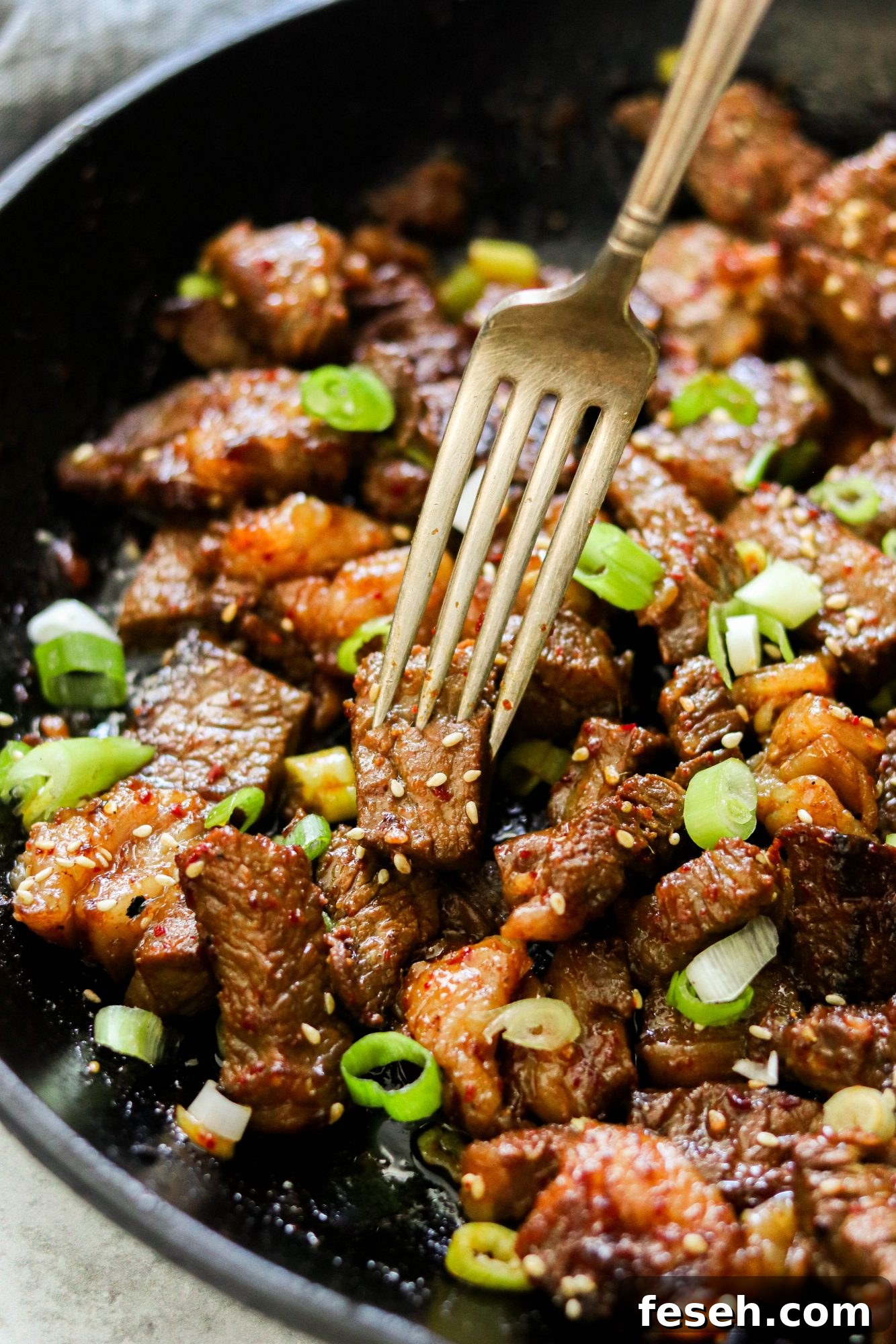 Fork lifting a glazed Korean steak bite, showing charred edges and juicy center.