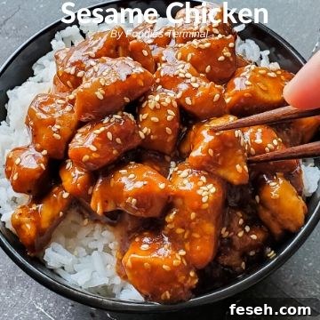 Sesame Chicken on rice in a black bowl with chopsticks