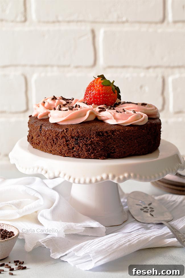 Chocolate cake with strawberry frosting on white cake stand