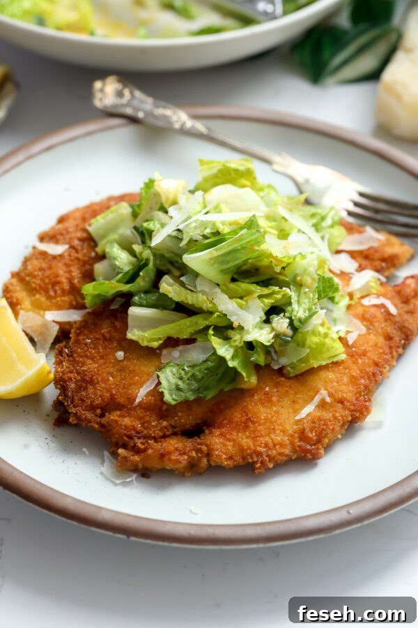 Crispy chicken Milanese with a fresh Caesar salad on top.
