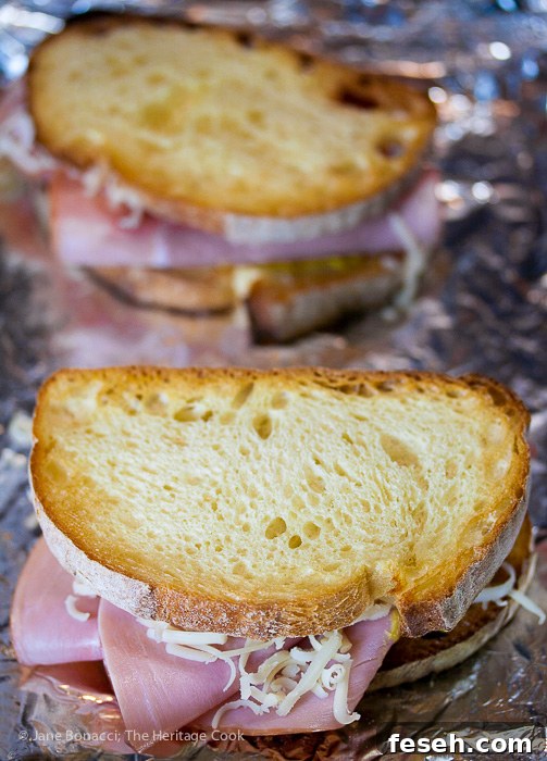 Assembling the sandwiches, layering ham and cheese inside with more cheese on top