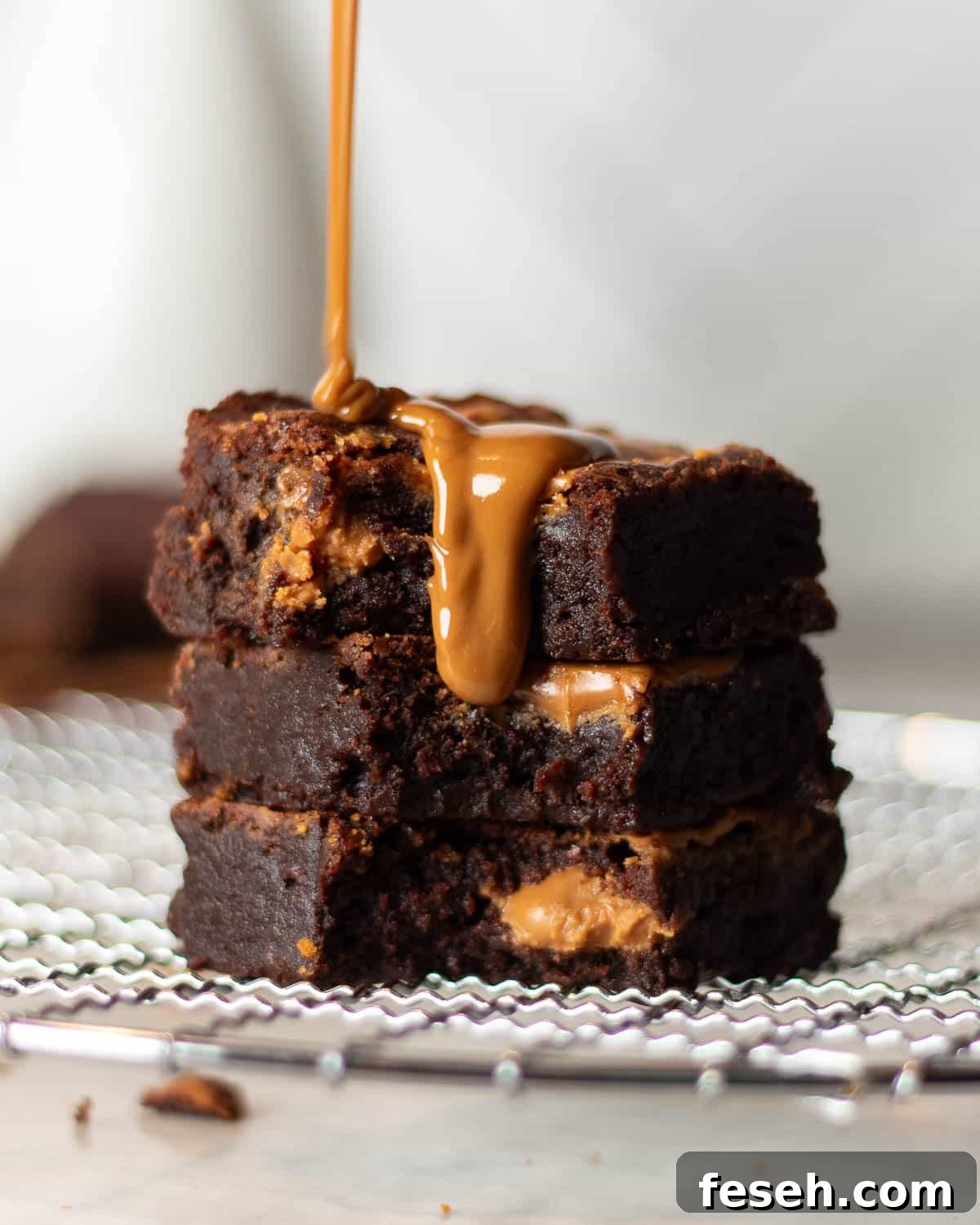 Artful pour of caramel over Biscoff brownies with a luxurious cascade of sauce, ideal for a Biscoff brownies dessert menu.