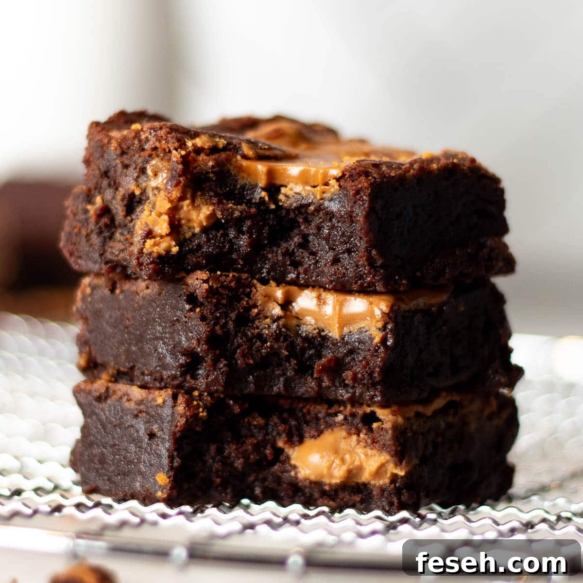 Stack of three Biscoff brownies with visible chunks of Biscoff spread, suitable for a post on decadent Biscoff brownie variations.