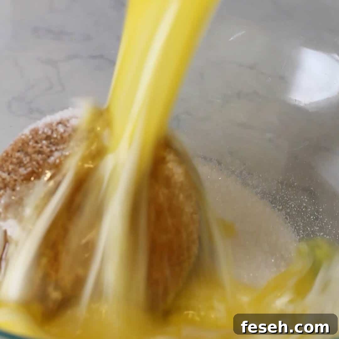 Pouring melted butter into a bowl of dry ingredients, including brown sugar and white sugar, beginning the moist and delicious biscoff brownie batter.