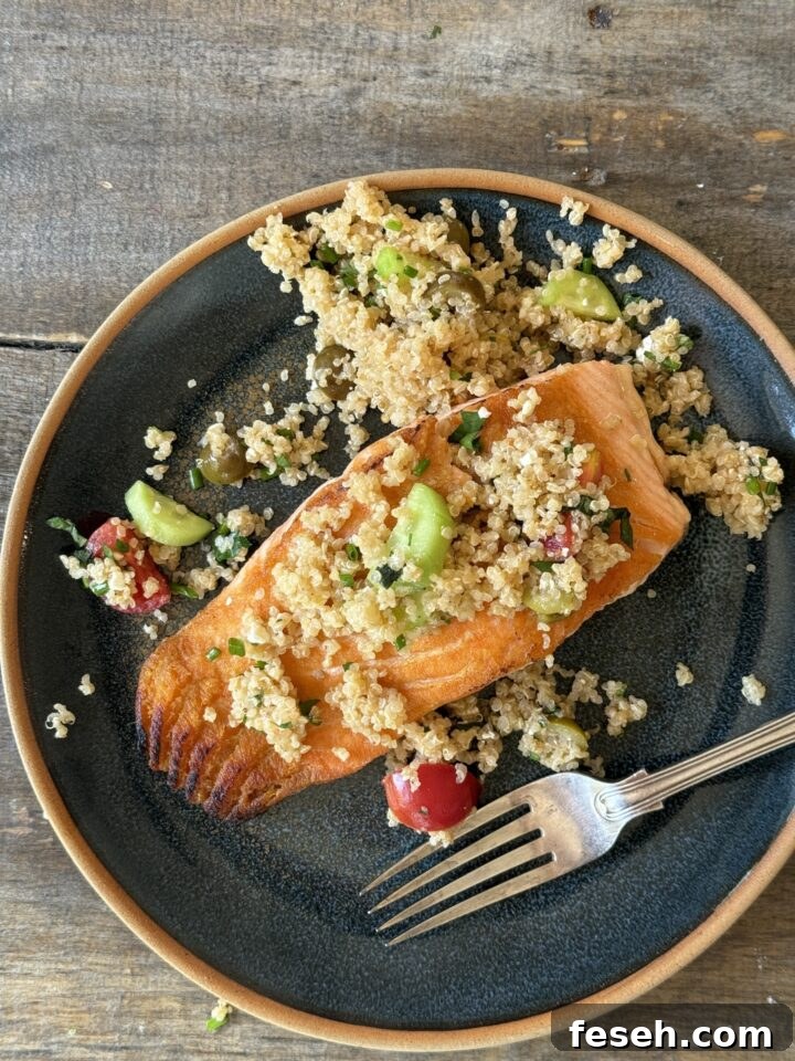 an above view photo of salmon on a blue plate with quinoa salad on top