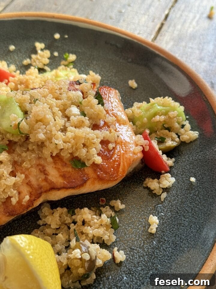 a close up photo of salmon with greek quinoa salad on a blue plate