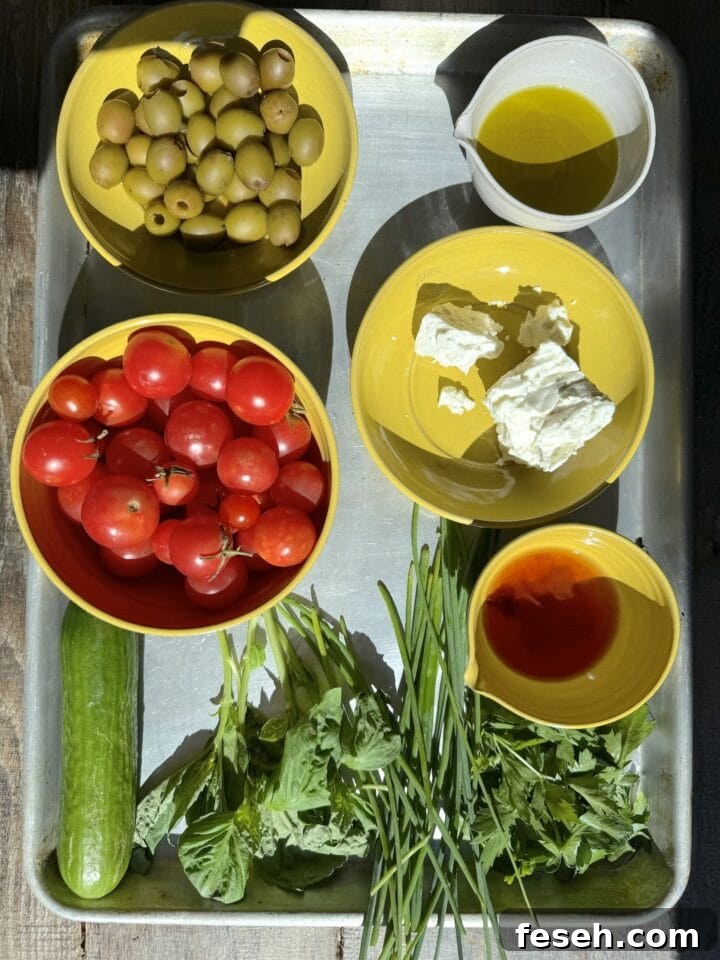 Fresh green and red tomatoes, herbs, olive oil, and cheese on a metal tray, showcasing ingredients for homemade cooking.