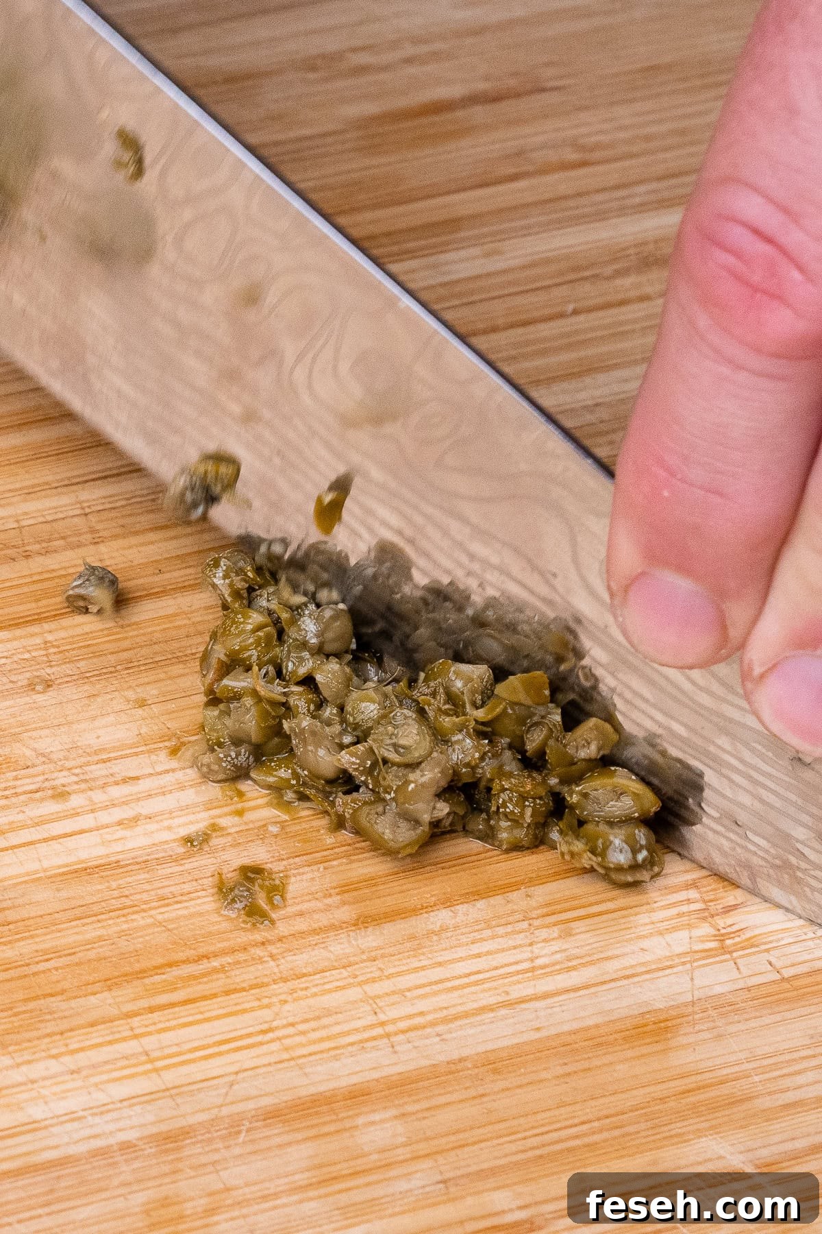 Chopping up capers on a chopping board