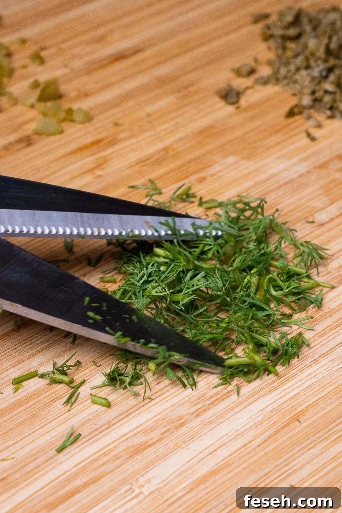 Chopping up a fresh dill on a chopping board using scissors