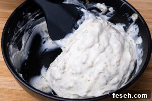 Stirring Mayonnaise, chopped capers, Gerkin, and dill with lemon juice together with a spoon