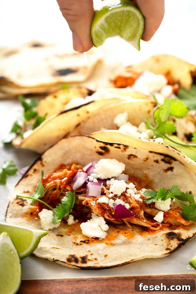 Squeeze of lime juice over Tinga chicken tacos