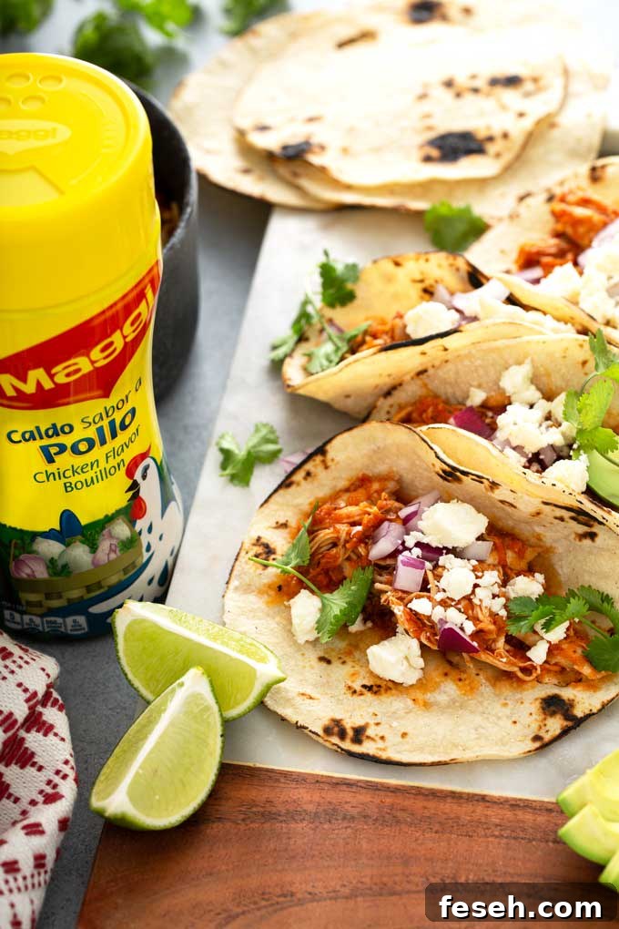Close up view of a shredded chicken taco topped with cotija cheese, onions and cilantro,