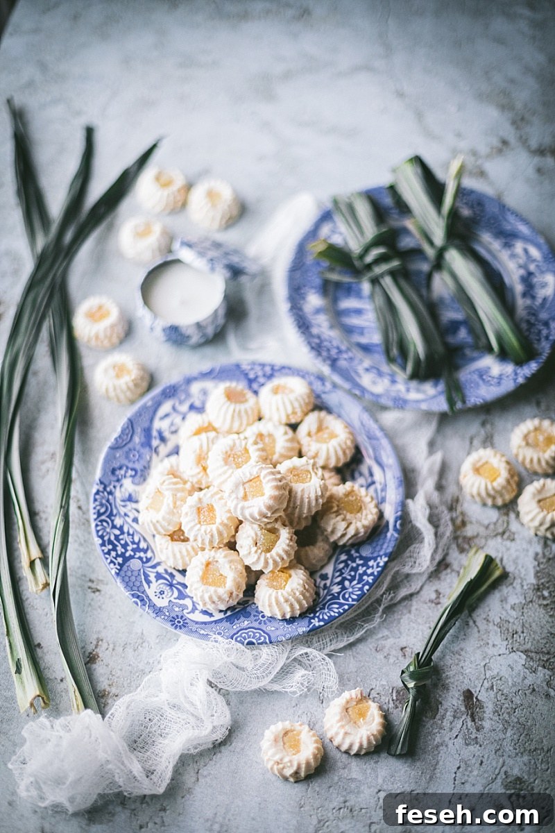 two blue china plates one with pandan leaves and one piled high with indonesian cookies on crackled concrete backdrop 