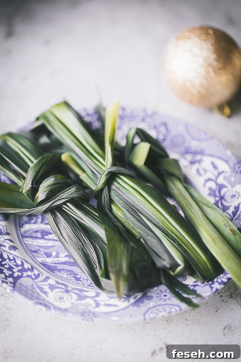 Three bunches of pandan leaves tied together sitting on a blue and white decorative plate