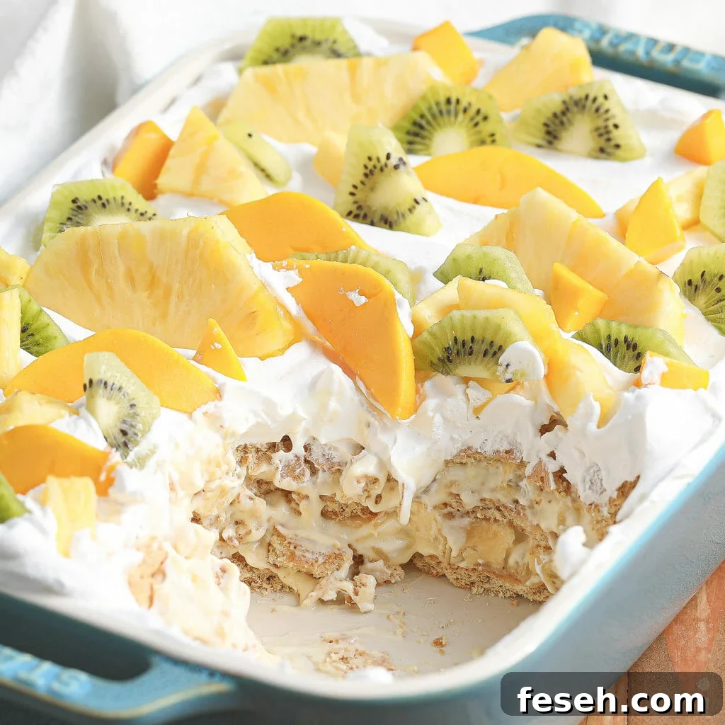 No-bake tropical icebox cake topped with whipped topping, pineapple, mango, kiwi, and banana