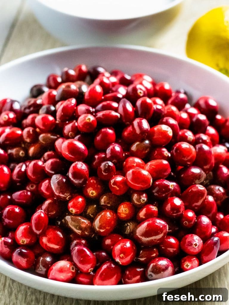 red cranberries in a bowl next to lemon and white bowl