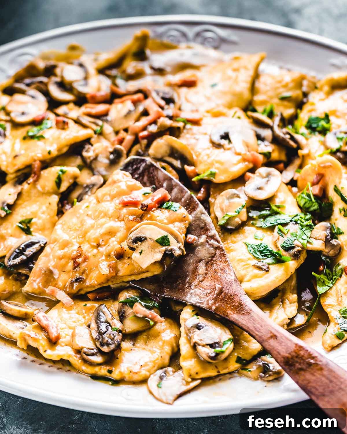 Spatula holding piece of finished chicken marsala over large platter.