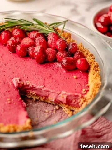 A piece taken out of cranberry tart garnished with cranberries.