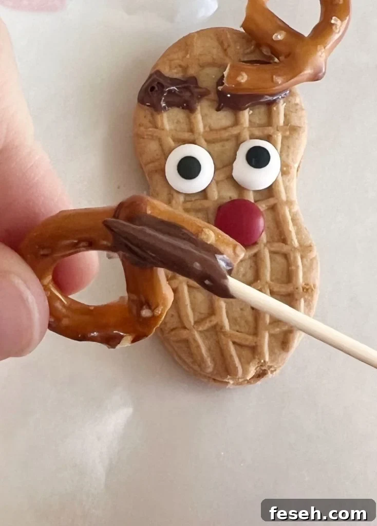 melted chocolate on pretzel antler for reindeer cookie