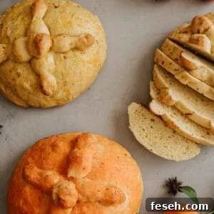 Traditional Pan de Muerto bread decorated with bone-shaped dough, surrounded by fresh oranges and star anise on a gray background.