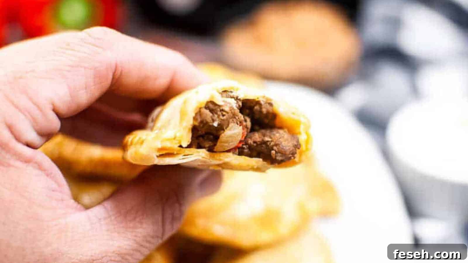 A hand holding an empanada that is broken open so you can see the inside filling.