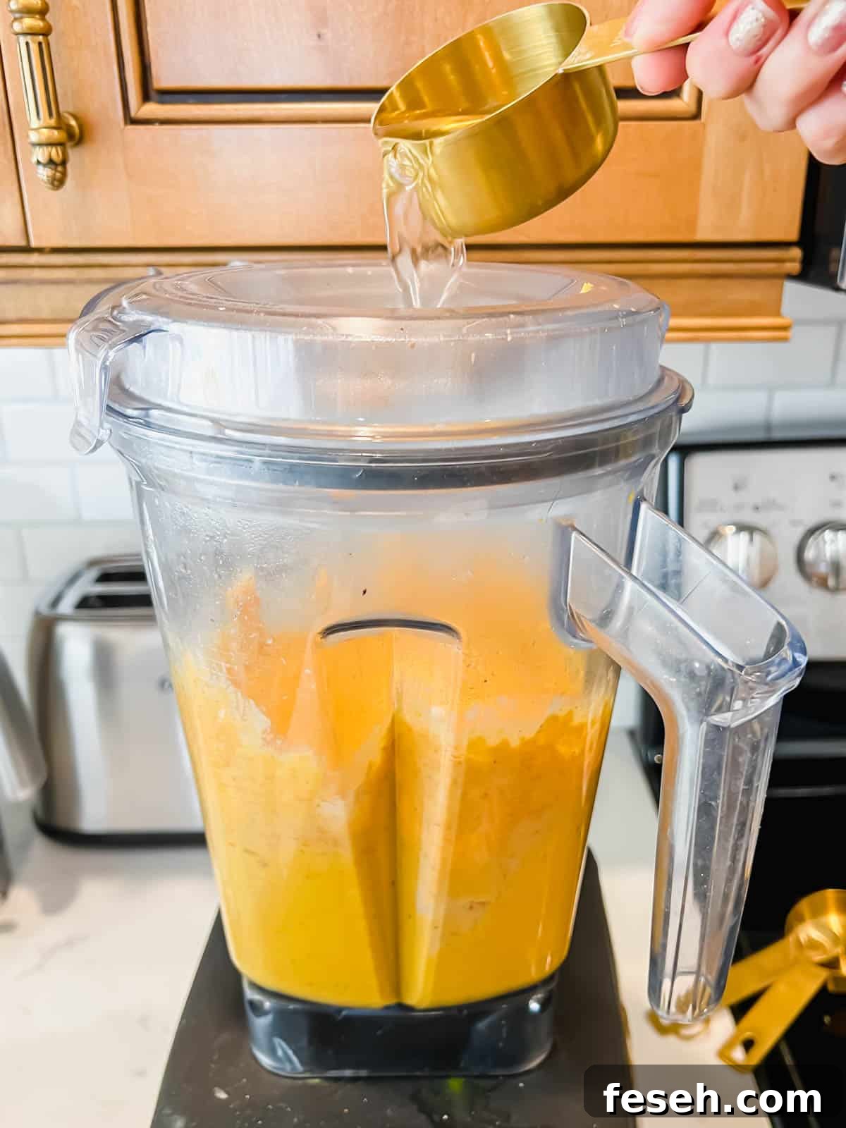 Water being poured into the blender while the hummus is mixing.