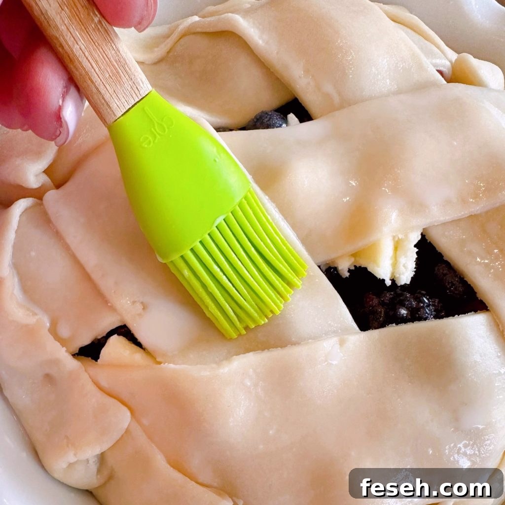 Brushing pie crust with milk.