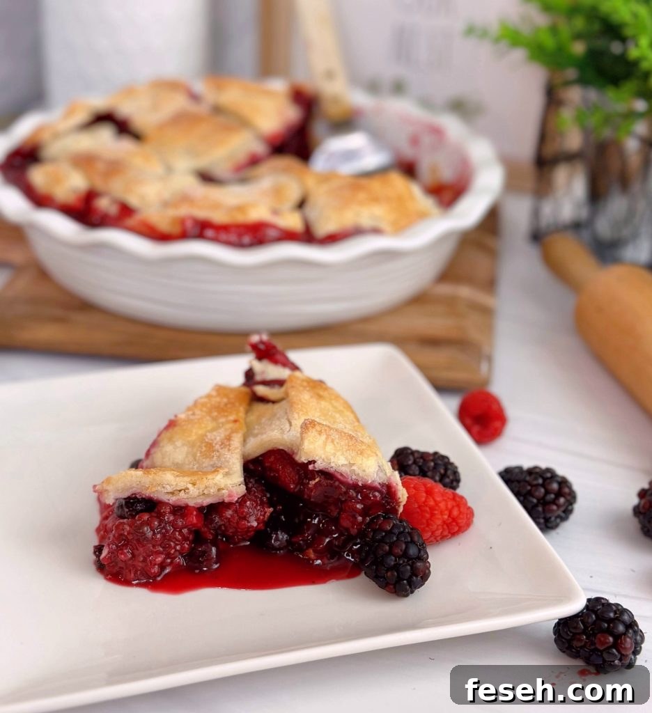 Triple Berry Galette in the background with a slice of the galette in the front on a white plate with berries all around it.
