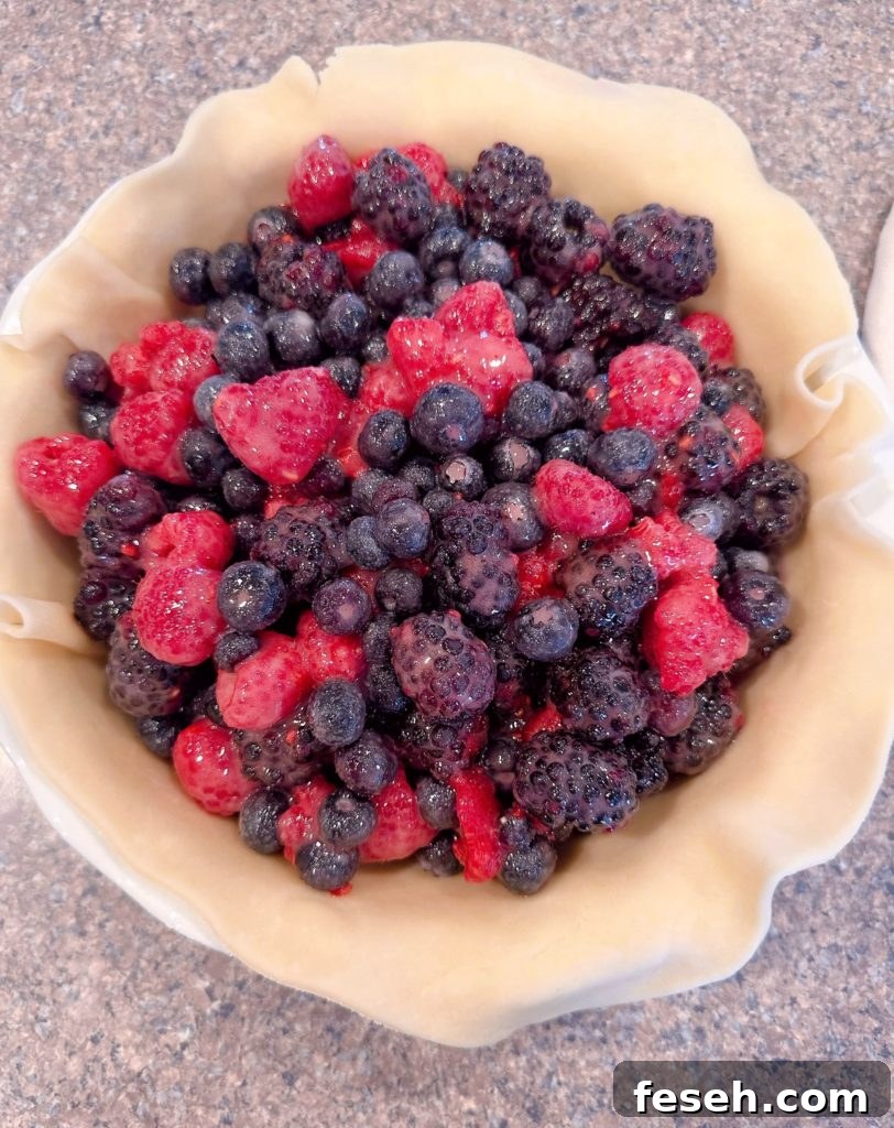 Adding the berry pie filling to the pie crust lined pie.