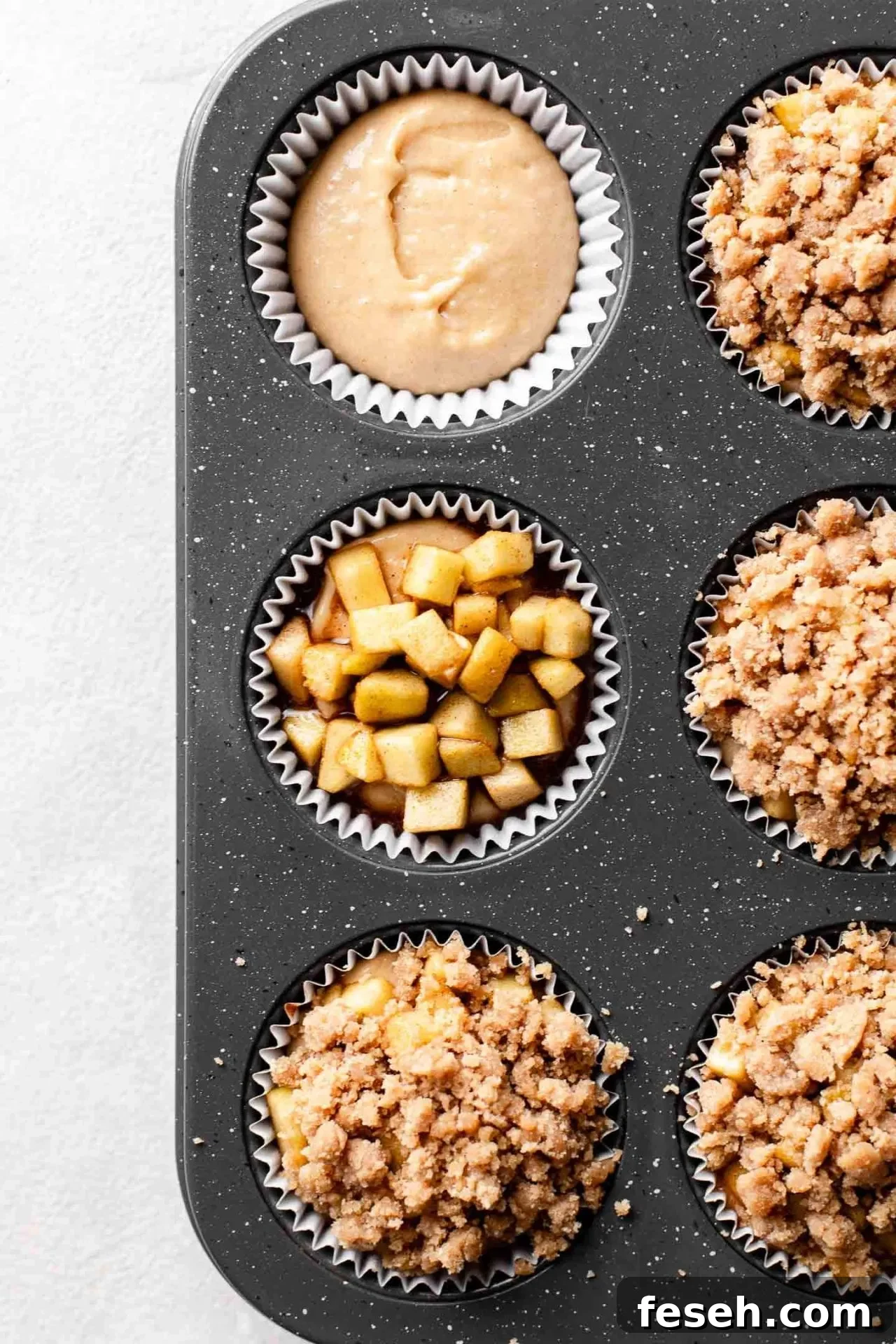 apple crumb muffin batter, apples, and streusel being layered together in muffin tin