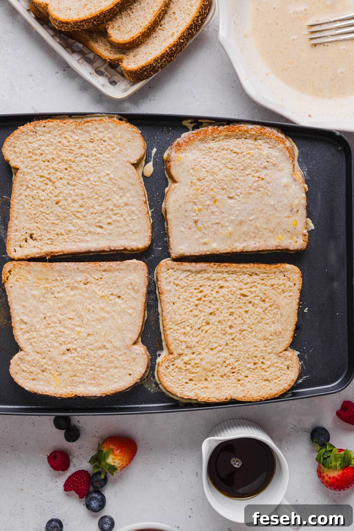 Four pieces of soaked bread on a skillet to cook the french toast.