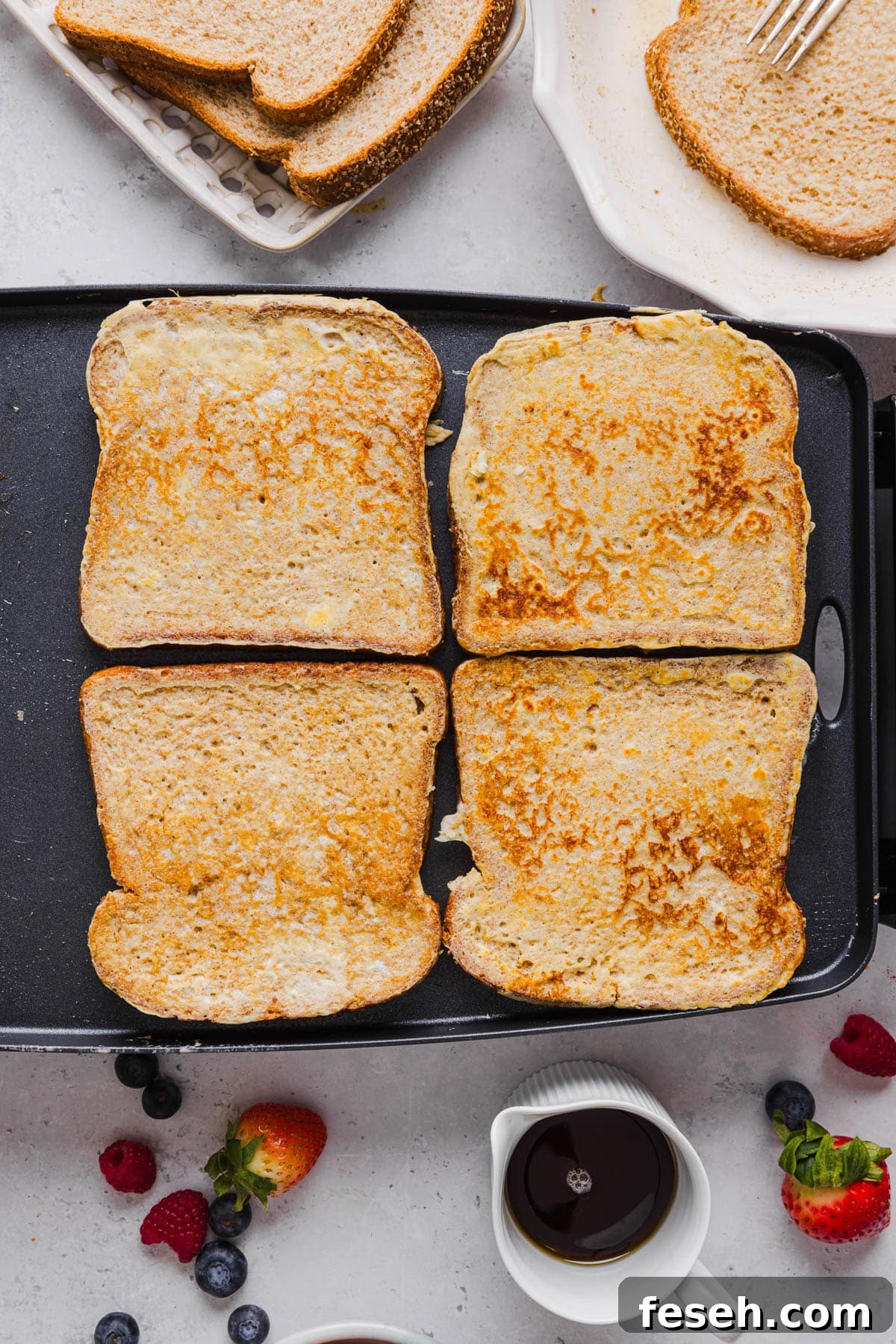 Four pieces of cooked french toast cooked until golden brown on a skillet ready for serving.