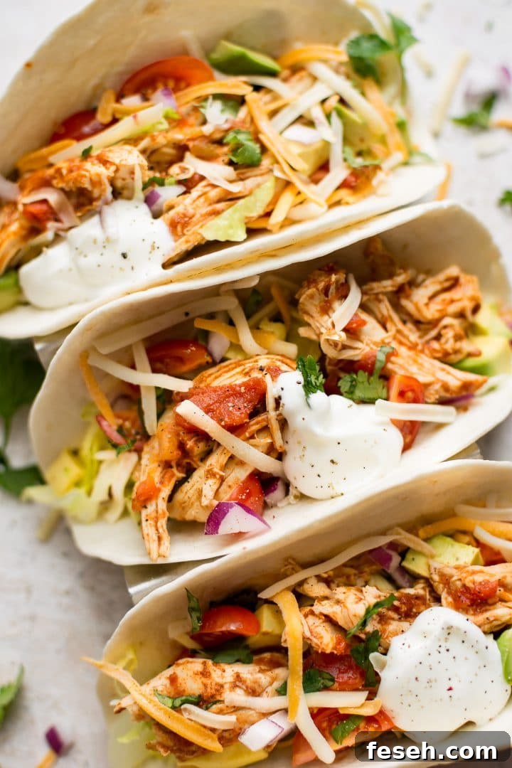 close-up of three Instant Pot chicken tacos topped with sour cream