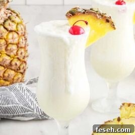 Pina Colada in a glass topped with a cherry and a slice of pineapple