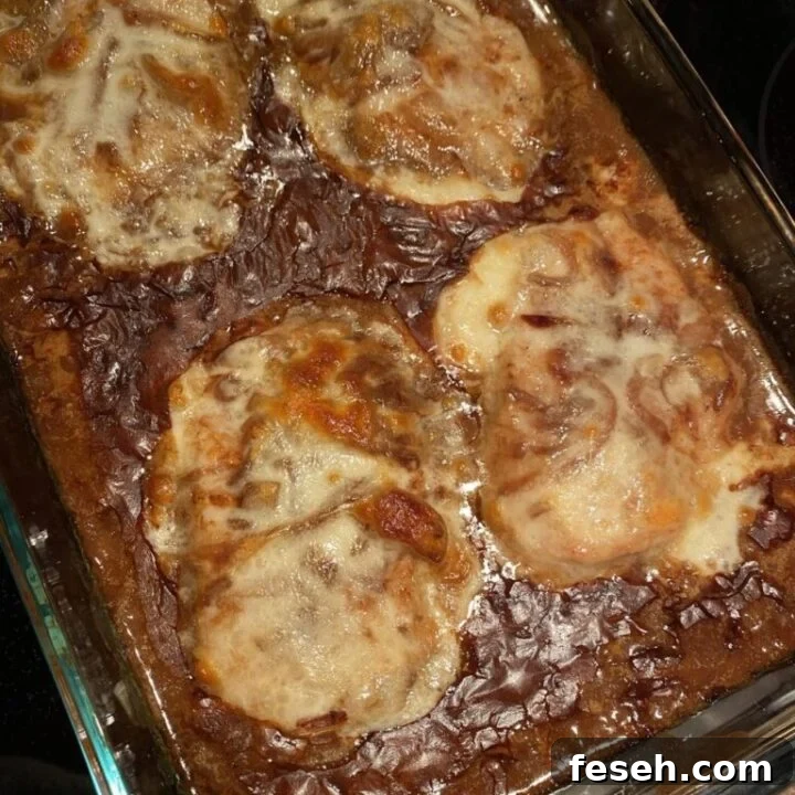 Baking dish with a brown onion gravy with boneless thick cut pork chops smothered in a white provolone cheese.