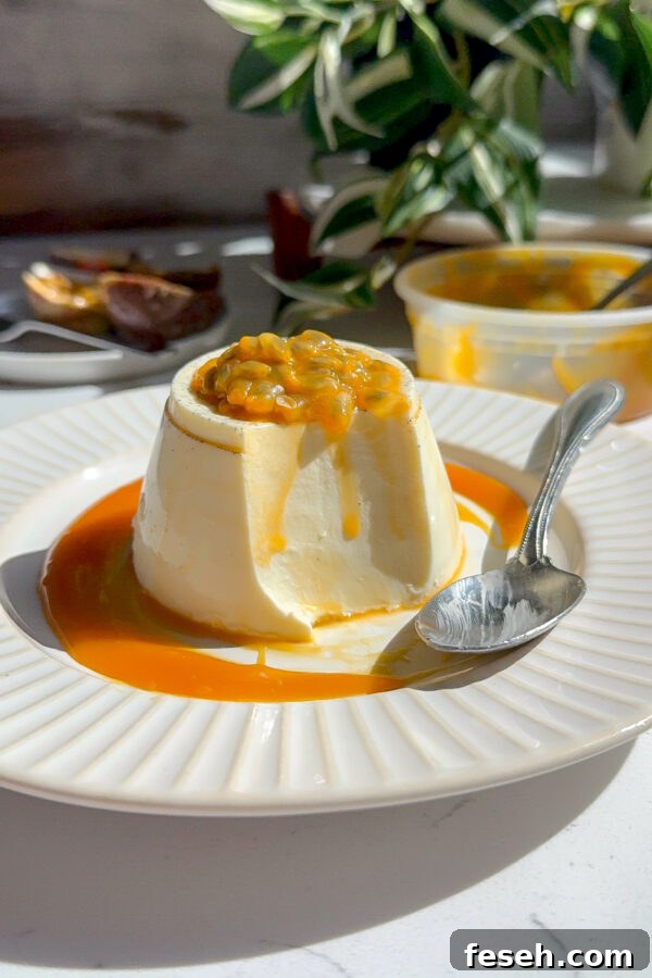 Creamy smooth Panna Cotta with a passion fruit caramel topping with a spoon next to it and a piece taken out to show how creamy the middle is.