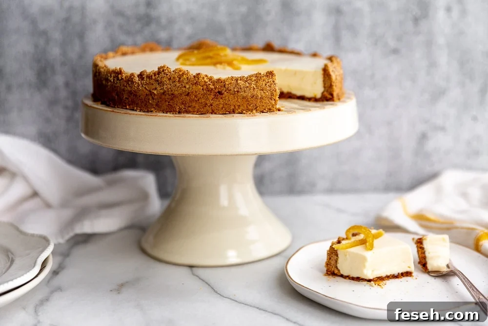 Creamy lemon pie with almond crust on cake stand, with a piece of pie on a plate.