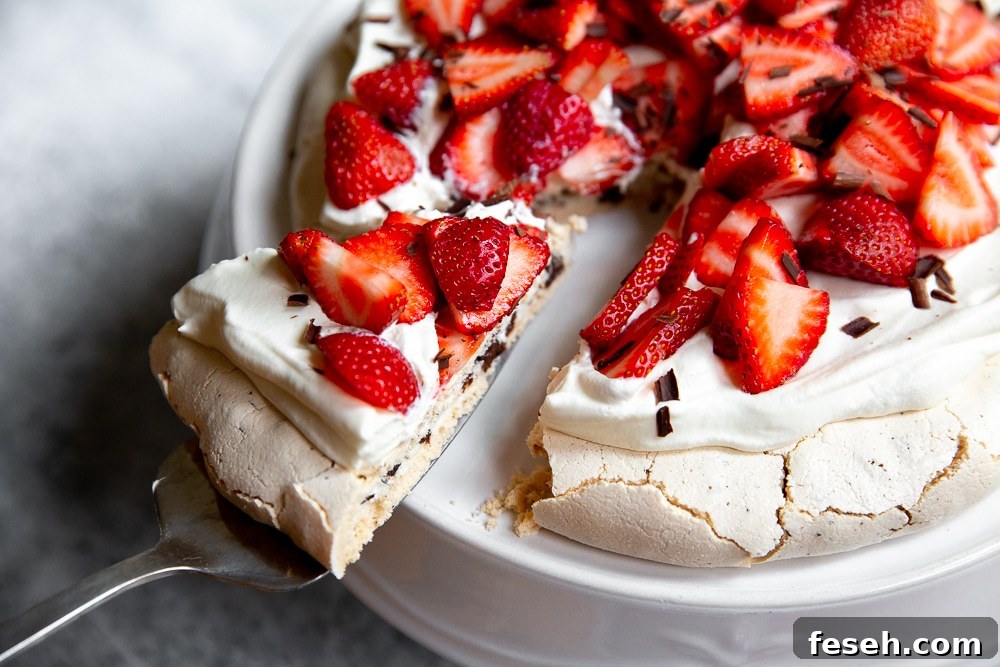 A slice of pavlova topped with whipped cream and strawberries.