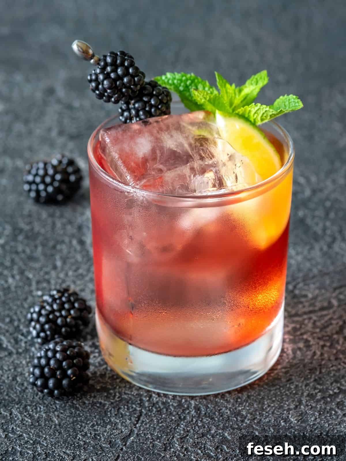 Blackberry smash and lime in whiskey glass.