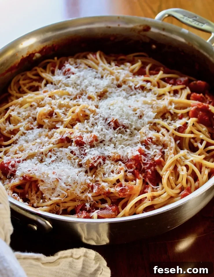 Spaghetti with Bacon Sauce, in skillet with grated cheese on top