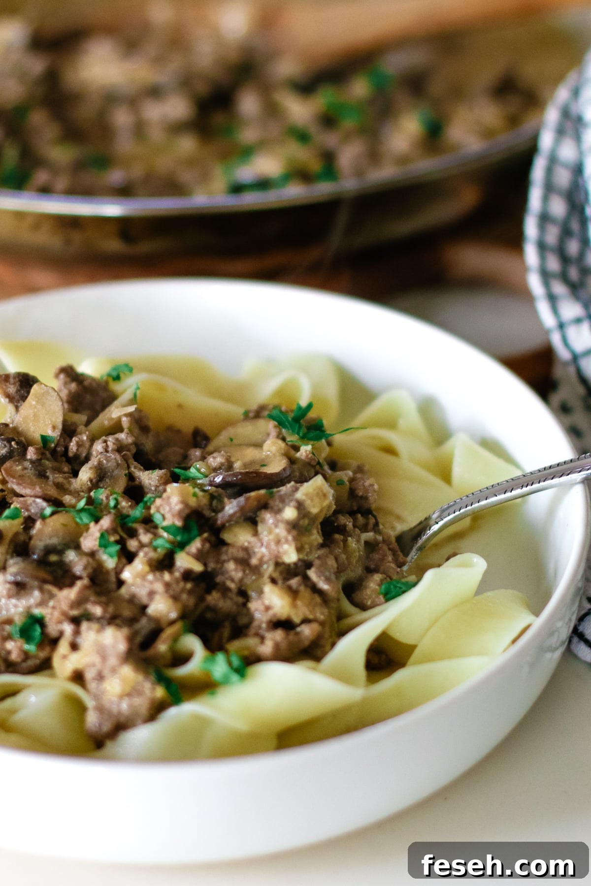 pasta with ground beef stroganoff in a small bowl topped with herbs.