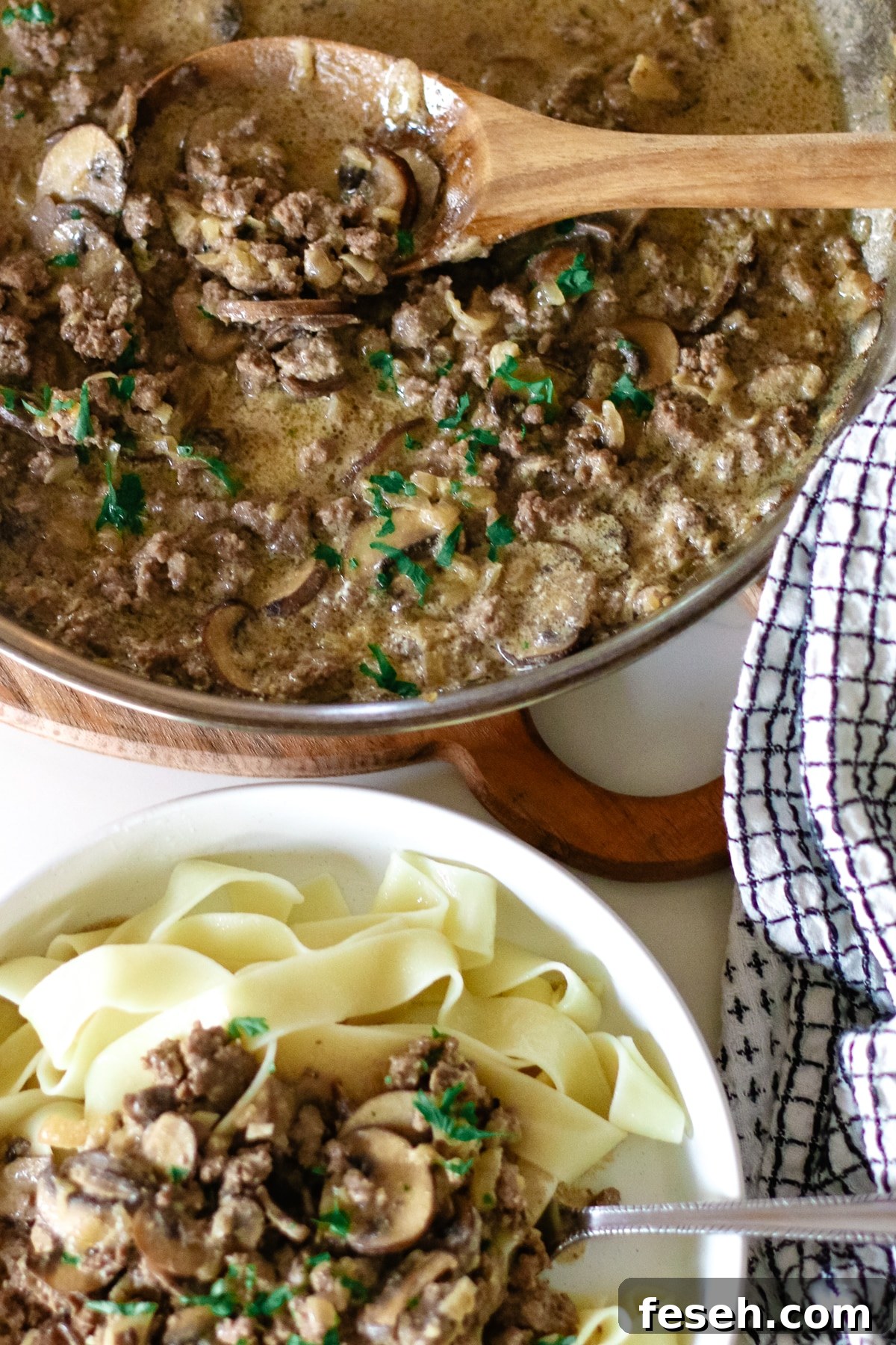 pasta with ground beef stroganoff in a small bowl topped with herbs.