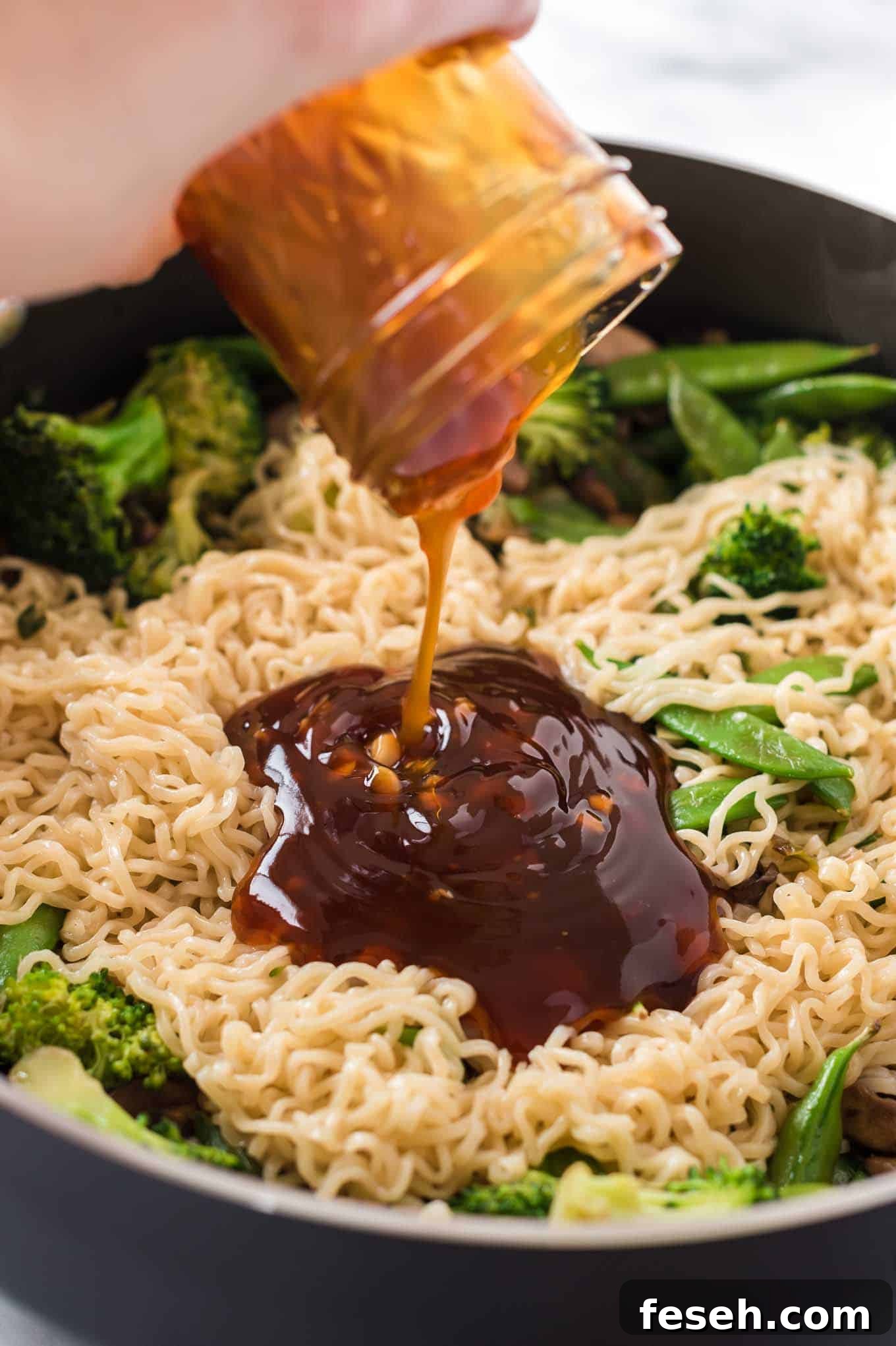 teriyaki sauce being poured onto a stir fry