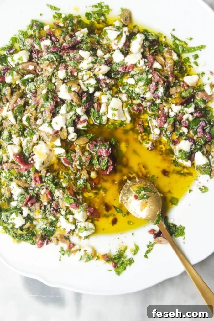 Small gold spoon in Greek style bread dipping oil in a large white plate.