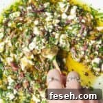 Hand mixing ingredients for Greek dipping oil in a large white plate.