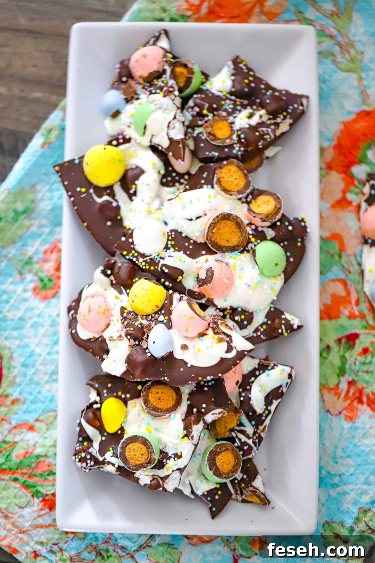 Easter malted milk ball bark with dark chocolate, white chocolate drizzle, marshmallows, and pastel candy pieces on a plate.