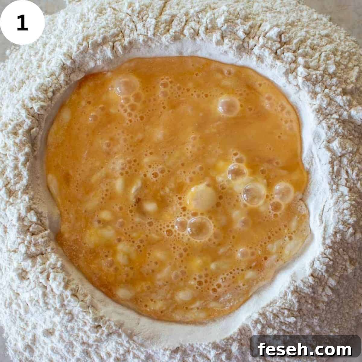 Beaten eggs in a well of flour.