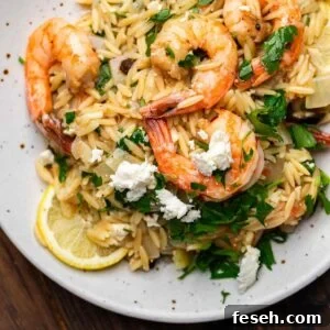 Orzo with shrimp and feta in white plate.