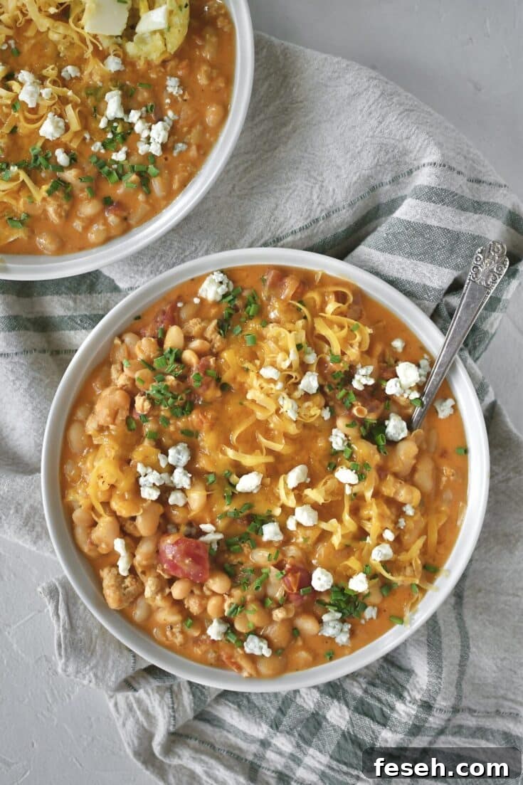 Buffalo Chicken Chili served in a bowl, topped with chives, blue cheese, and cheddar cheese.